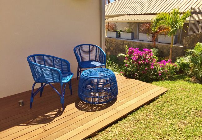 Deux fauteuils bleus en résine tressée sur une terrasse en bois au milieu du jardin fleuri – Villa Naézora, villa 10 personnes avec piscine à Saint-Gilles-les-Bains, La Réunion