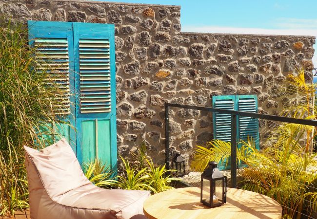 Le coin terrasse avec son mur en pierre et ses volets décoratifs – Villa Naézora, villa 10 personnes avec piscine à Saint-Gilles-les-Bains, La Réunion