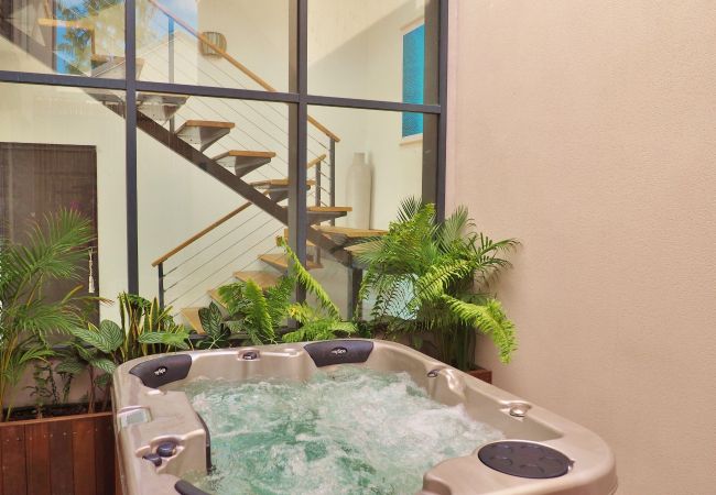 Le jacuzzi intérieur entouré de plantes sous une grande verrière – Villa Naézora, villa 10 personnes avec piscine à Saint-Gilles-les-Bains, La Réunion