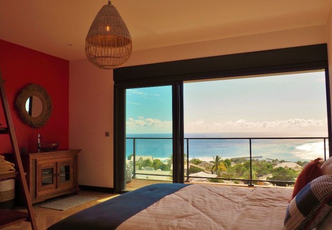 Chambre avec mur rouge et grande baie vitrée sur l’océan – Villa Naézora, villa 10 personnes avec piscine à Saint-Gilles-les-Bains, La Réunion