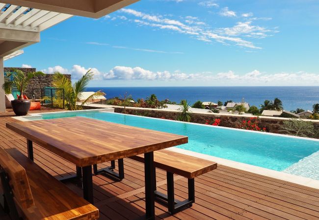 La table en bois au bord de la piscine face à l’océan – Villa Naézora, villa 10 personnes avec piscine à Saint-Gilles-les-Bains, La Réunion