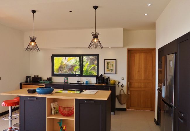 La cuisine et son îlot central en bois clair – Villa Naézora, villa 10 personnes avec piscine à Saint-Gilles-les-Bains, La Réunion