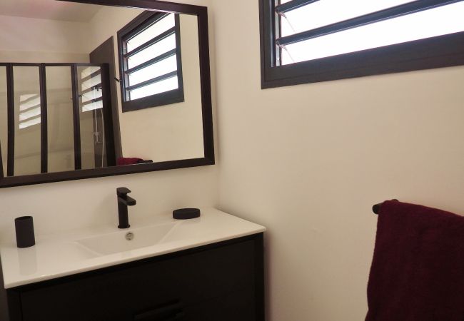 Salle d’eau avec meuble noir, vasque blanche et miroir – Villa Naézora, villa 10 personnes avec piscine à Saint-Gilles-les-Bains, La Réunion